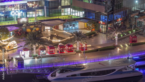 Dubai marina promenade on waterfront along canal aerial night timelapse.