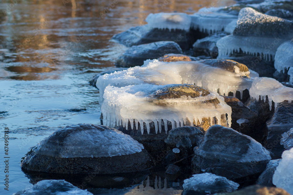 Fototapeta premium Winter landscape with ice and stones on frozen Sea. Ice frozen on a stone. Sea shore in winter, covered with ice and snow