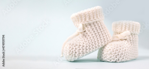 Crochet white baby booties, on a gray background, handmade baby booties, warm baby feet is a guarantee of health. space for text photo