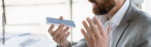 Fotografía Cropped view of businessman recording voice message on smartphone with blank screen, banner