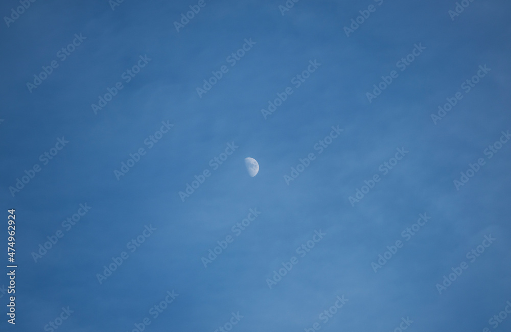 Moon in the clouds, blue sky.