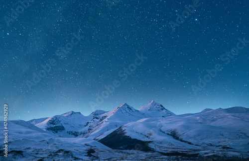 Snow covered mountains under starry sky. Night landscape. © Inga Av