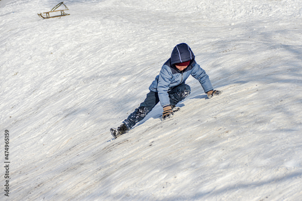 A child climbs a snow slide for sledging.