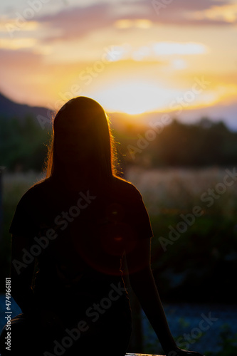 Silhouette of young teen girl sitting on the bench