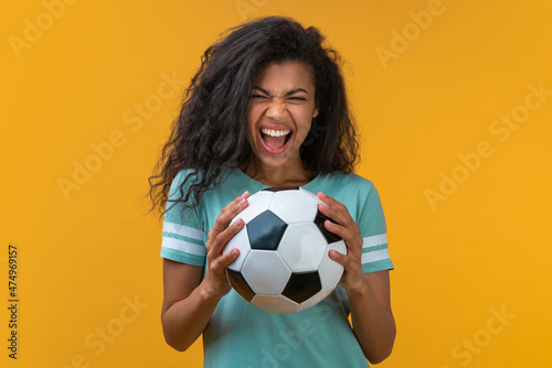 Portrait of football fan girl with the ball in hands smiling and saying "yeah", being happy to support favorite team © wpadington