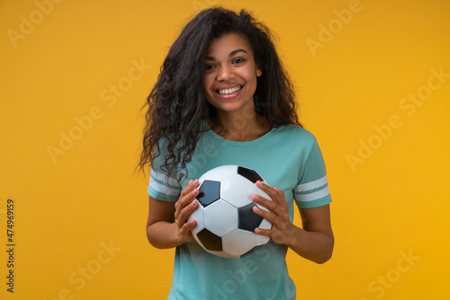 Studio shot of attractive confident smiling soccer player girl posing with a ball in hands © wpadington