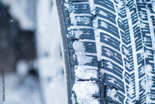 Closeup view of winter tires on a road covered with snow in cold freeze winter months. © annamaria