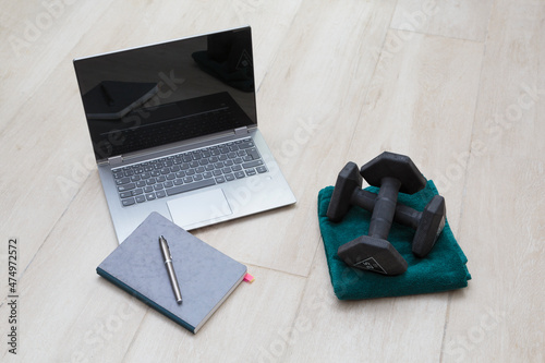 A laptop, a notebook and a pair of dumbbells