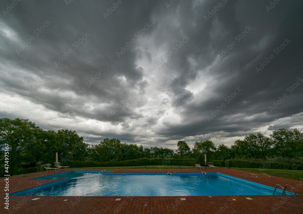 Empty swimming pool with storm clouds implying disappointment.