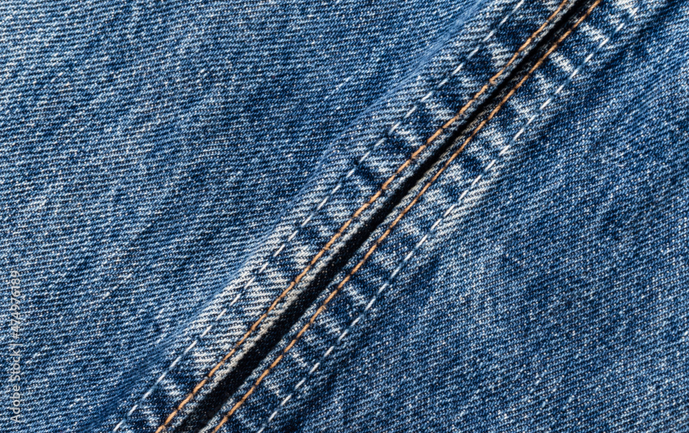 Blue denim fabric with double stitching on jeans trousers close-up Blue denim fabric with double stitching on jeans trousers close-up
