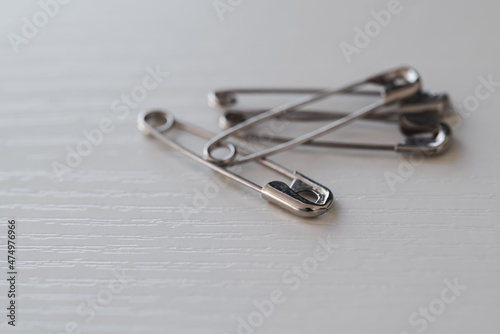 closeup of a pile of four metal safety pins on a white desk
