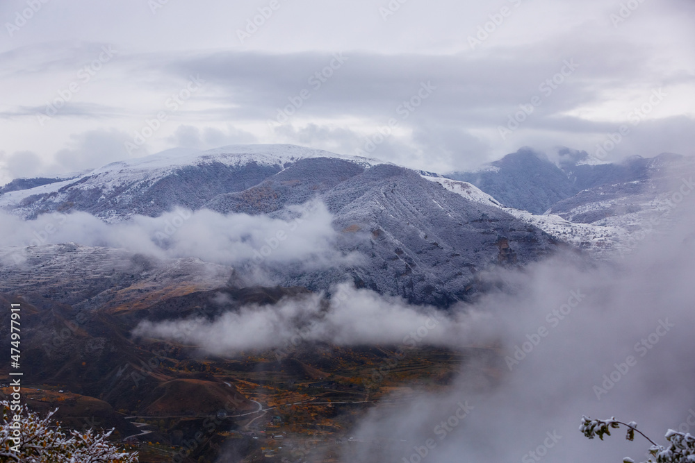 Panoramic view from the Gunib village, Dagestan, Russia. Snow-capped mountains and autumn fields. Beautiful mountain landscape in winter. Foggy forest hills