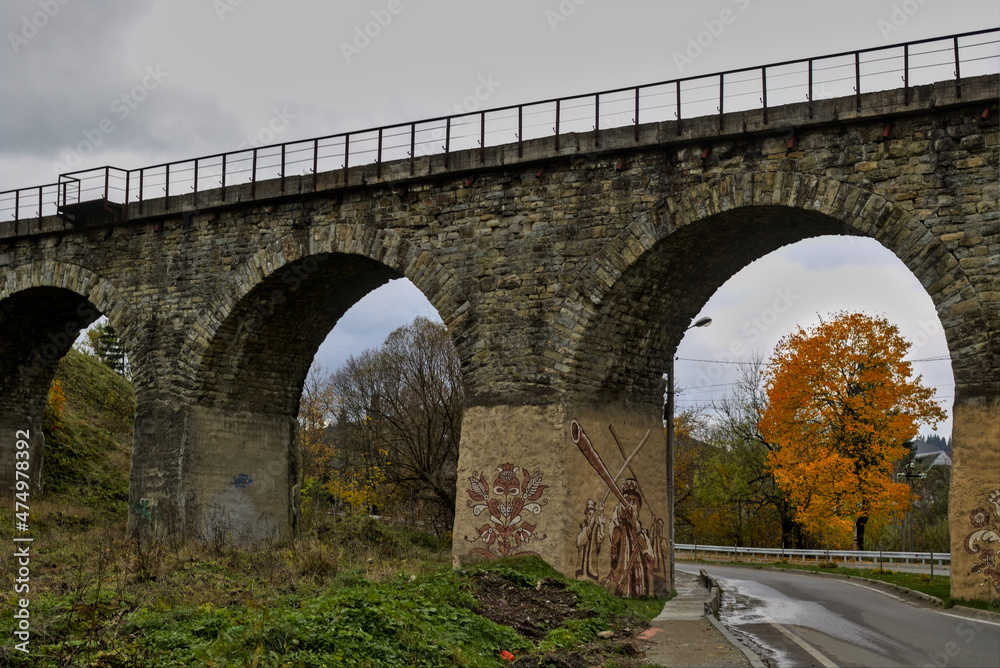 Old Austrian bridge viaduct in Vorokhta village the Carpathians Ukraine. Autumn mountain landscape - yellowed and reddened autumn trees combined with green needles.