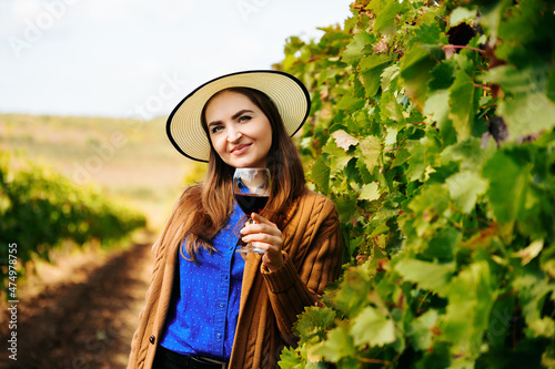 Canvas Print Attractive winemaker woman holding a glass of red wine in her hand and looking at the camera