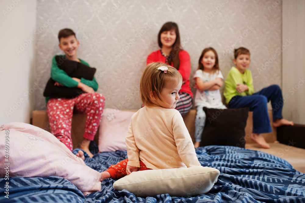 Happy big family is having fun together in bedroom. Large family morning concept. Mother with four kids wear pajamas in bed at home.