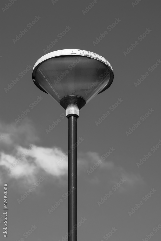Clean lines of a modern lamppost silhouetted against an even sky in black and white. Clean lines of a modern lamppost silhouetted against an even sky in black and white.