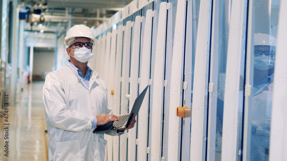 Male specialist with a laptop is inspecting factory cabinets Male specialist with a laptop is inspecting factory cabinets