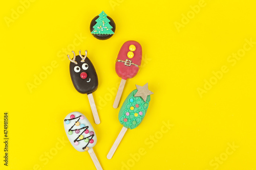 Set of different Christmas cookies donats and cakesicles on yellow background photo