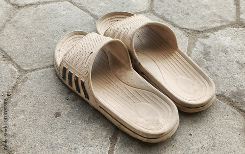 a pair of white sandals on a paving road, white rubber sandals isolated on a hexagon paving street background