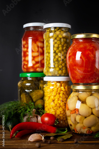 Jars of various pickled vegetables on a dark background. Canned food