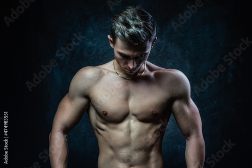 Young male athlete bodybuilder aestheticist posing against a dark background. Healthy lifestyle and sports concept.