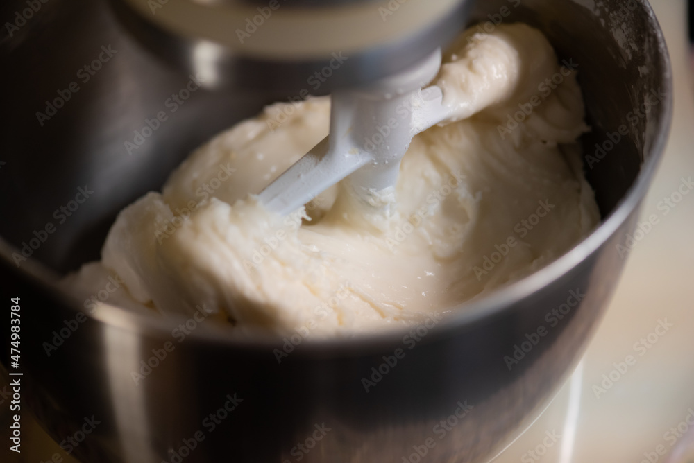 macro shot of kitchen mixer with white dough, royal icing being whipped. 