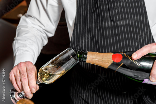The bartender's hand holds a glass of sparkling wine.
