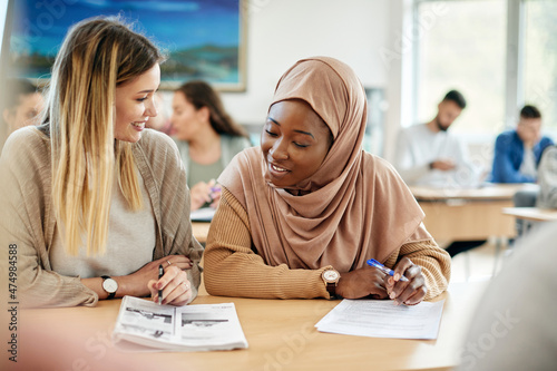 Obraz na plátně Happy Muslim student learning with her female Caucasian friend during class at the university