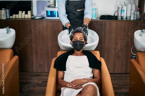 African American woman getting hair wash at hairdresser's during coronavirus pandemic. photo