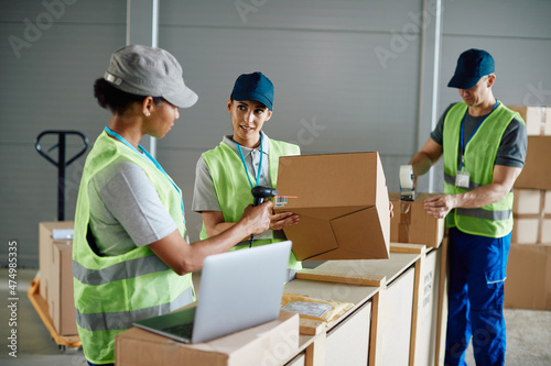 Young warehouse worker and her colleagues organizing the shipment of packages at distribution logistics center.