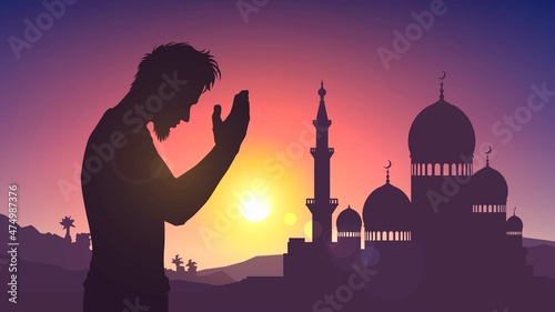 Valokuva Silhouette of a mosque and a praying man on the background of sunset or dawn
