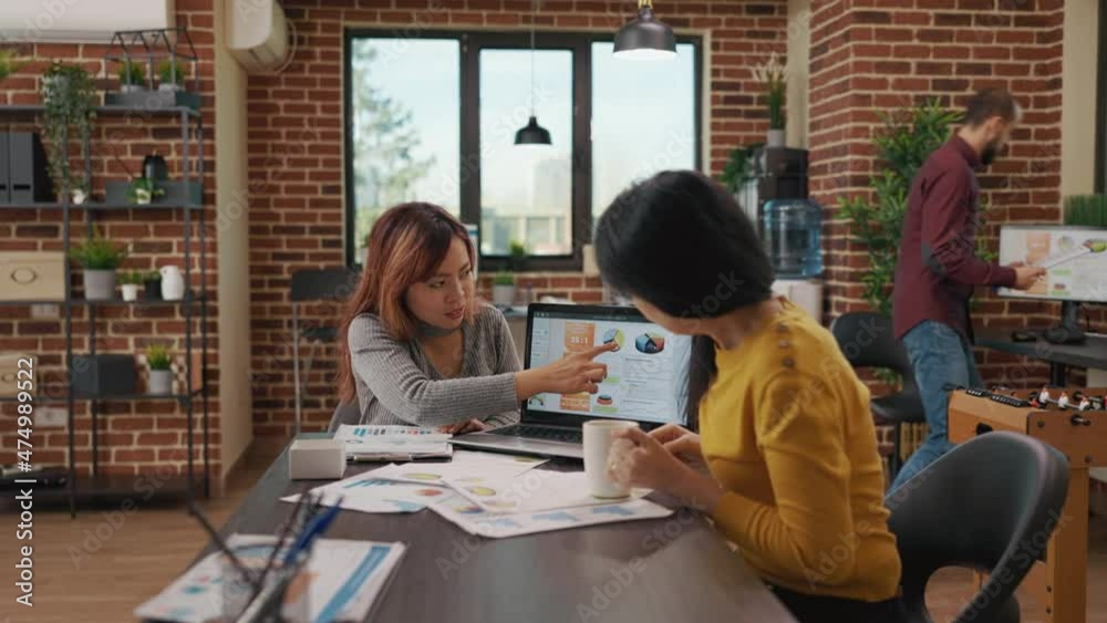 Asian women planning marketing project in startup office, looking at files with sales analysis and annual company reports. Coworkers working on business growth, brainstorming ideas. Asian women planning marketing project in startup office, looking at files with sales analysis and annual company reports. Coworkers working on business growth, brainstorming ideas.