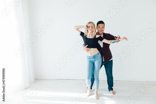 a woman and a man dancing to the music of a bachata in a white hall