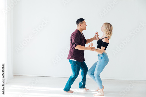 a woman and a man dancing to the music of a bachata in a white hall photo