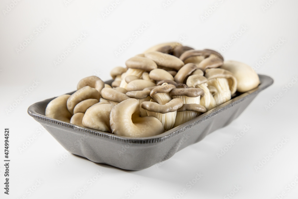 Pleurotus ostreatus packed in a foamed polystyrene tray, ready-to-sell mushrooms. White background. Safely packaged product Pleurotus ostreatus packed in a foamed polystyrene tray, ready-to-sell mushrooms. White background. Safely packaged product