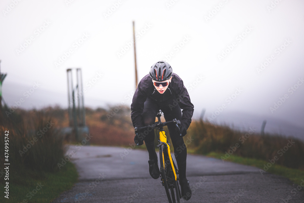 Obraz premium Young caucasian man sprinting on a road bike at the top of the mountain.