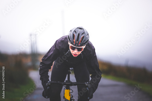 Young caucasian man sprinting on a road bike at the top of the mountain.