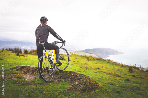 Young caucasian cyclist on the top of Jaizkibel mountain with views to the Basque Country.