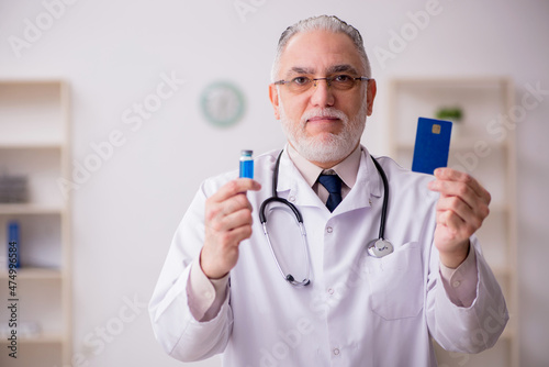 Old male doctor holding credit card