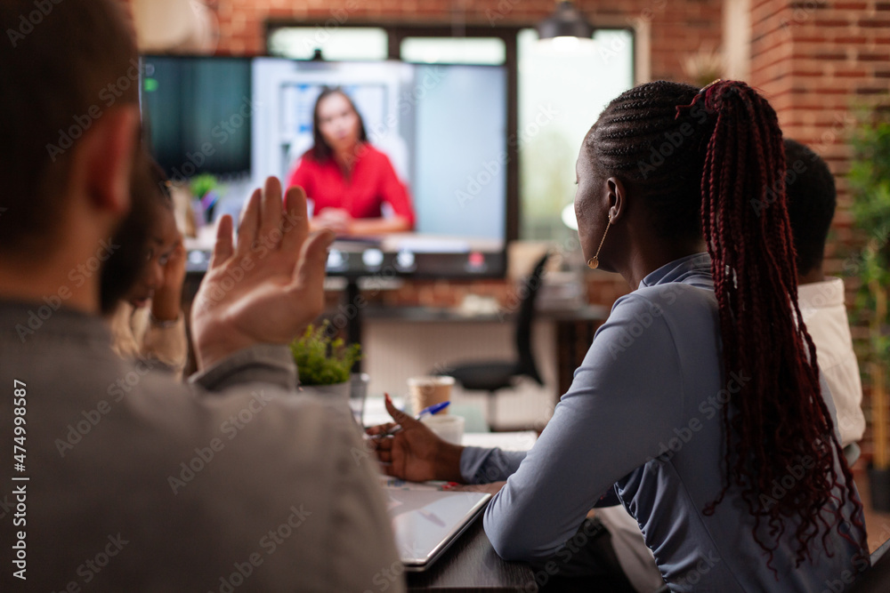 Multi-ethnic people discussing financial strategy with remote collegue working at company presentation during online videocall meeting conference in startup office. Business call on computer screen