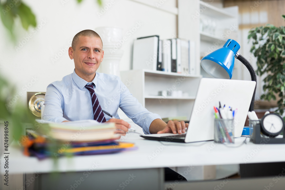 Obraz premium Caucasian male office worker sitting in his workplace and looking in camera.