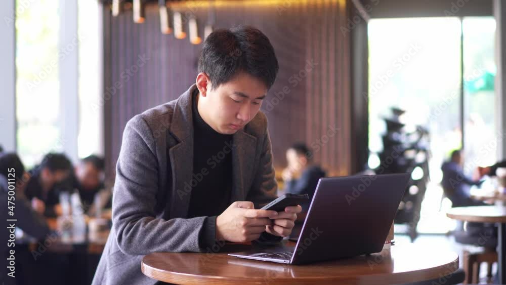 young chinese businessman using smart phone and laptop young chinese businessman using smart phone and laptop