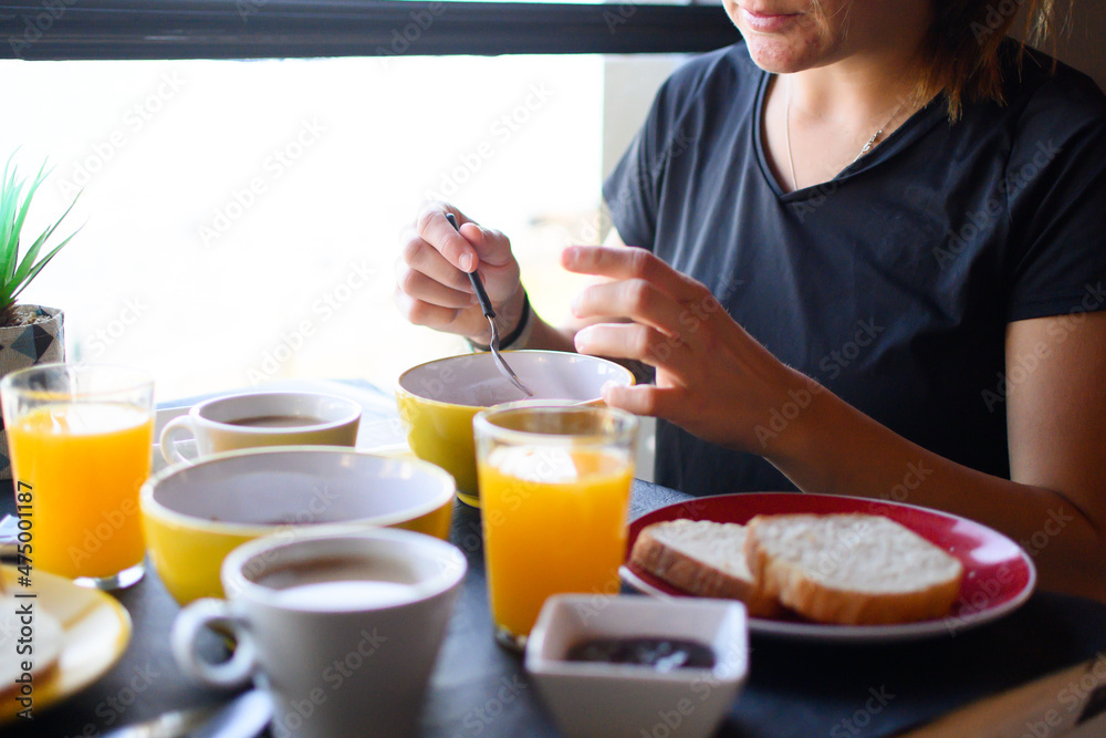 Young caucasian woman having breakfast near a window.