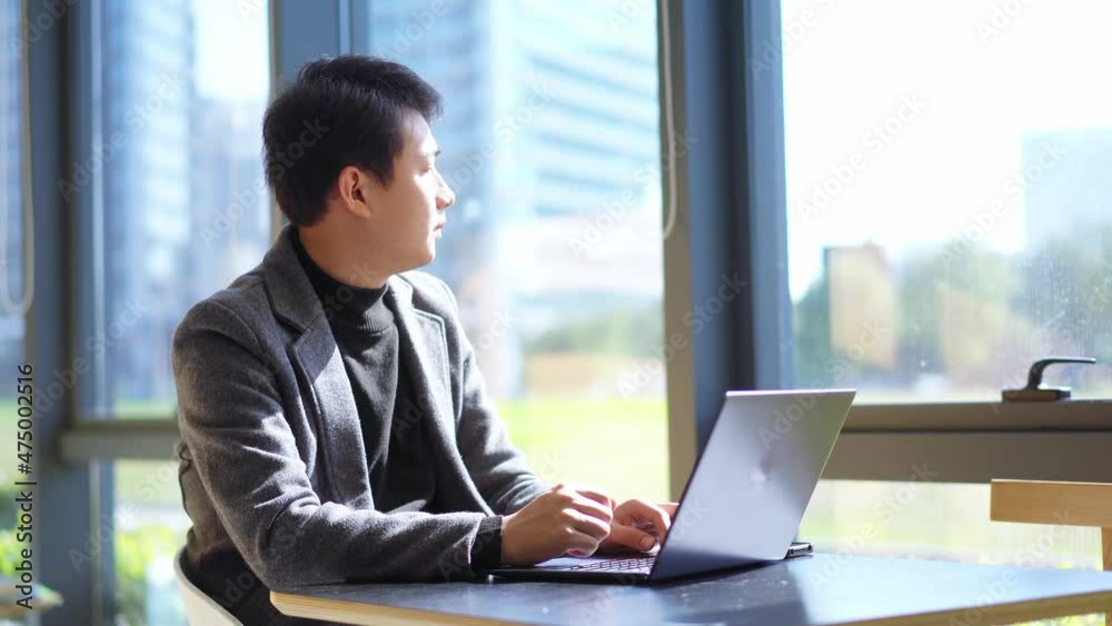 young chinese businessman using smart phone and laptop young chinese businessman using smart phone and laptop