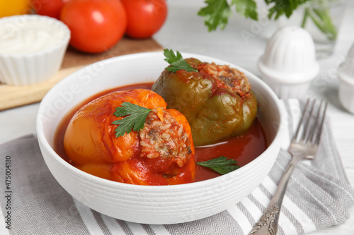 Delicious stuffed peppers with parsley in bowl on table