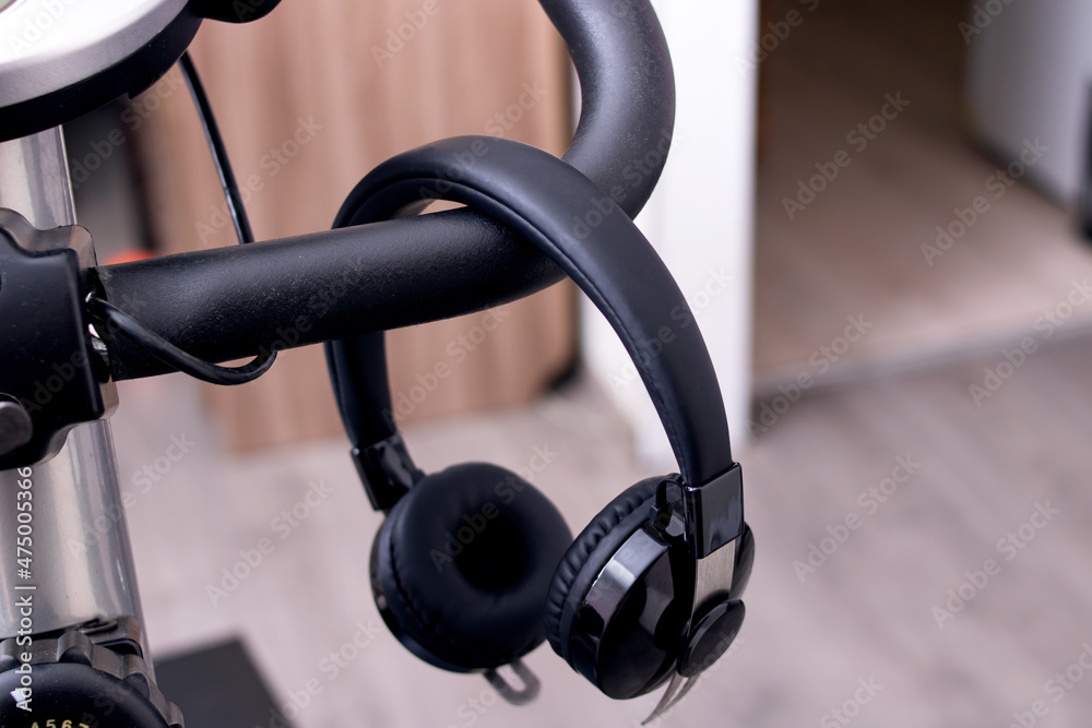 Headphones hang on the handlebars of the exercise bike Headphones hang on the handlebars of the exercise bike