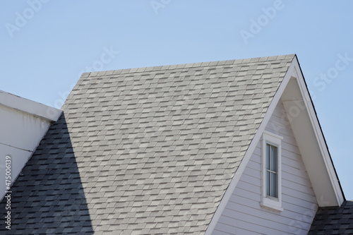 Roof shingles with garret house on top of the resident. dark asphalt tiles on the roof background.