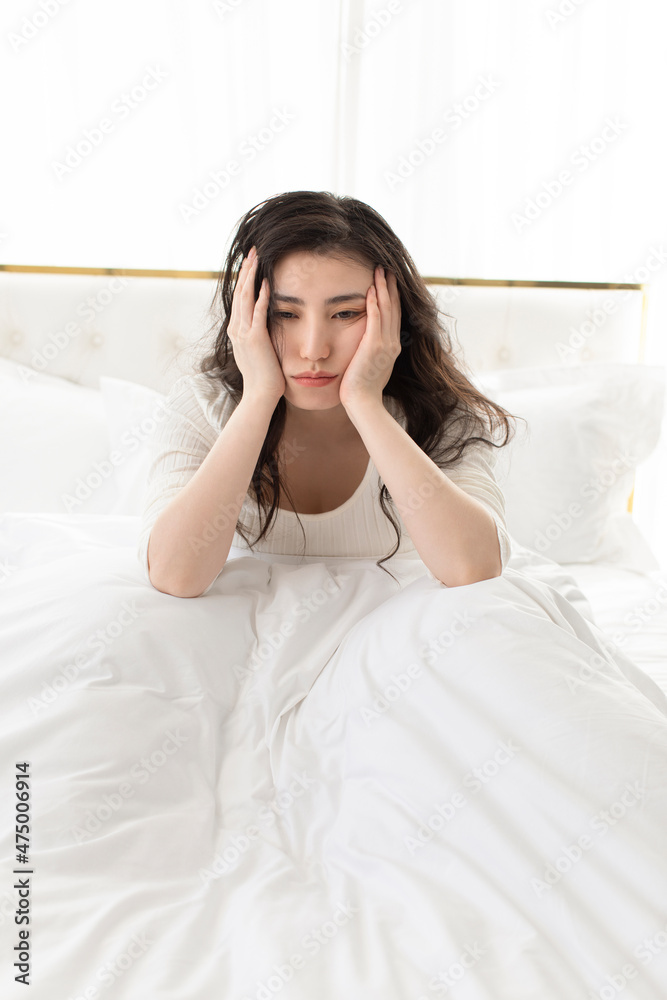 Displeased young woman sitting on bed Displeased young woman sitting on bed
