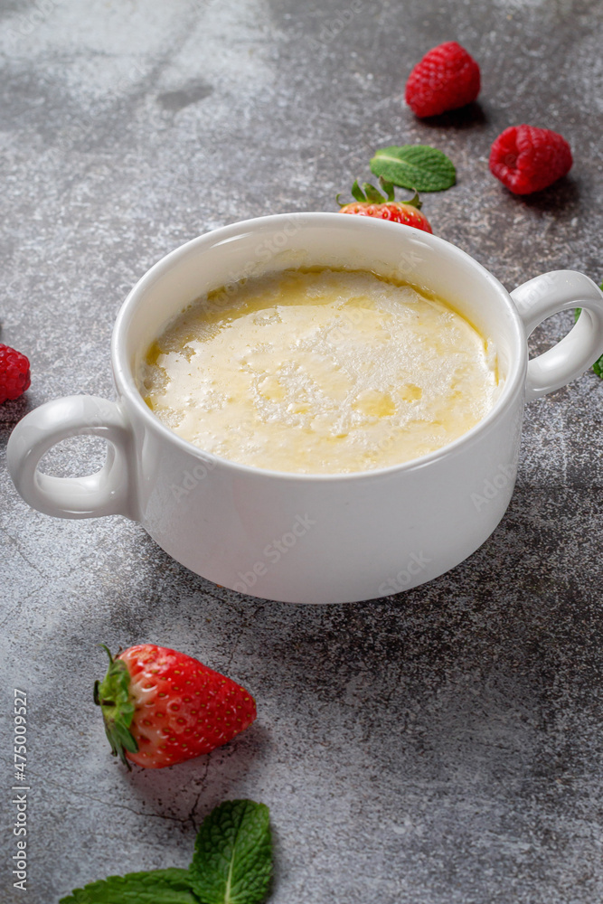 Cream of wheat, semolina pudding with butter and fresh raspberries and strawberries with mint in a white cup against a gray stone table. A healthy breakfast in a restaurant Cream of wheat, semolina pudding with butter and fresh raspberries and strawberries with mint in a white cup against a gray stone table. A healthy breakfast in a restaurant