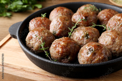 Tasty cooked meatballs served on wooden board, closeup photo